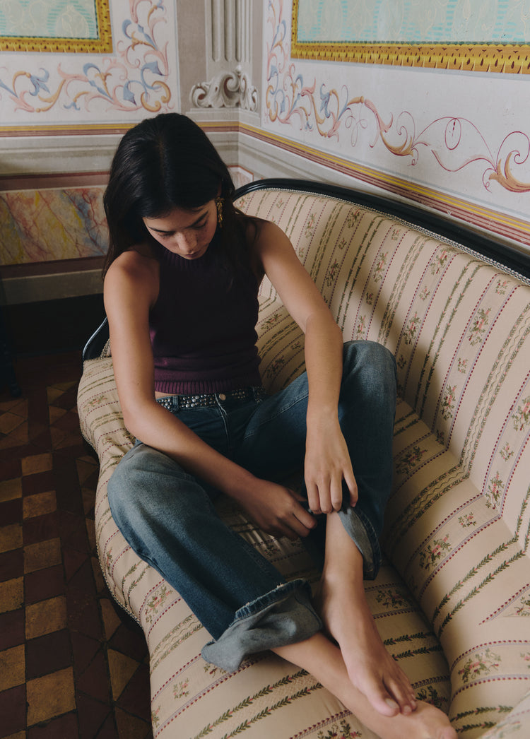 Top halter de color berenjena lucido en un look relajado sobre un sofá estampado