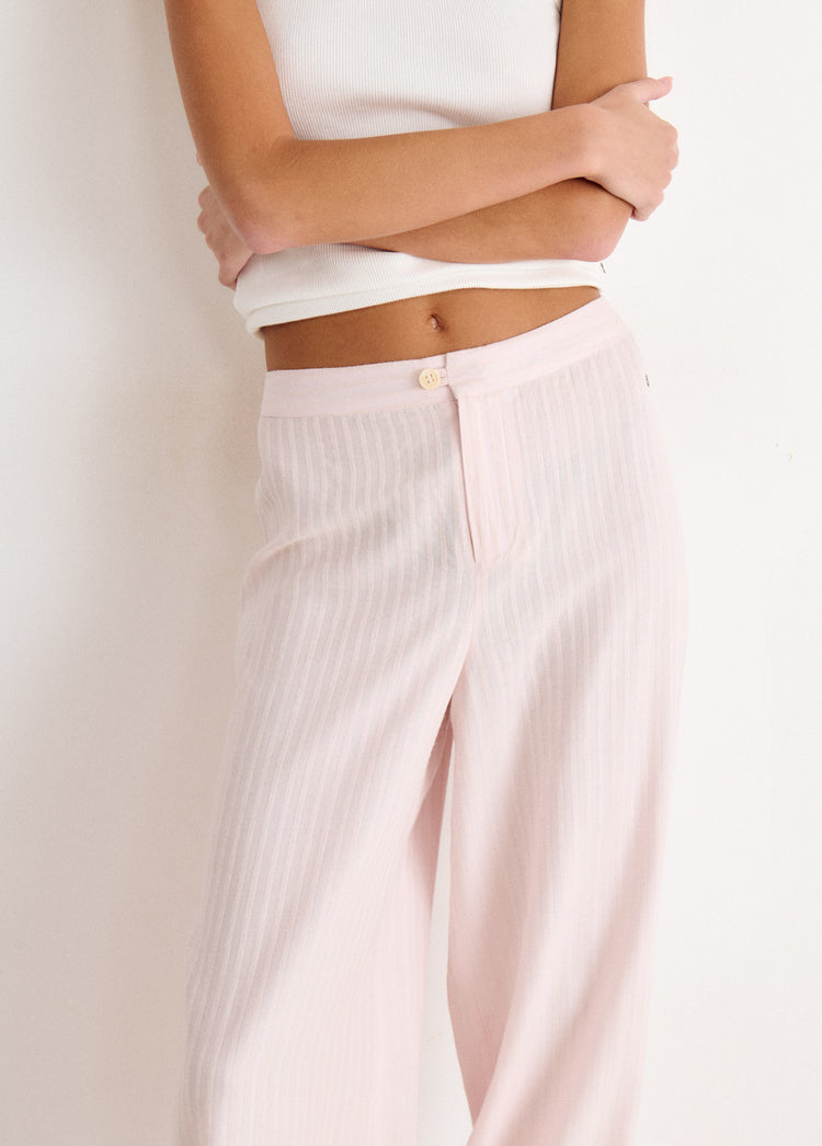 Pantalón largo bombacho de color rosa con textura de rayas verticales y botón dorado en la cintura