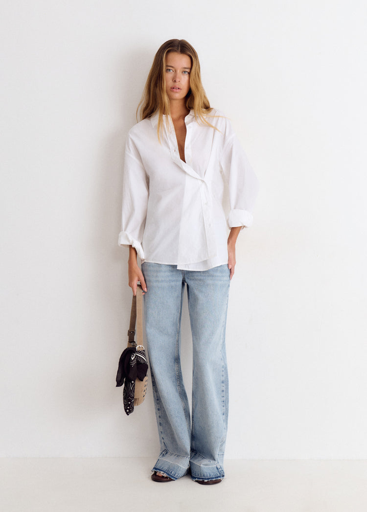 Blusa blanca de manga larga con cuello abierto y dobladillo asimétrico, vista de cuerpo entero