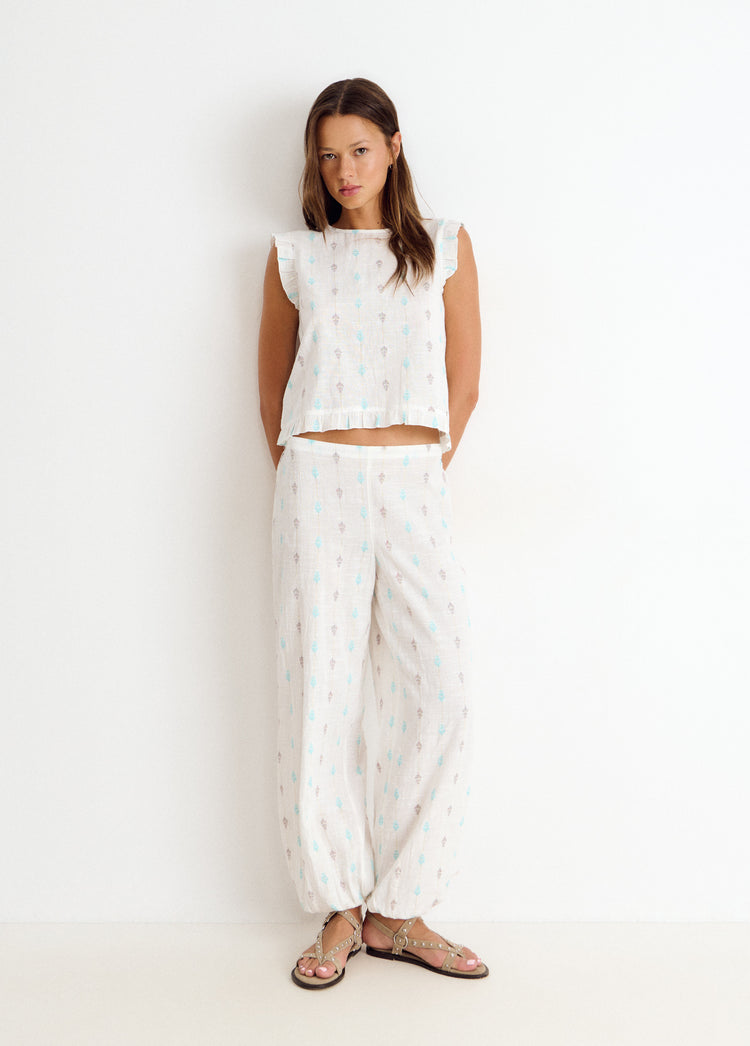 Blusa multiposición de color blanco con bordado y volantes en los hombros vista de frente