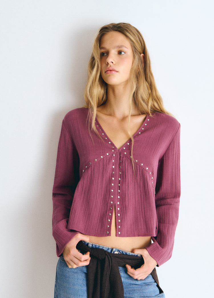 Blusa de manga larga en tono rosado con escote en V y detalles de tachas