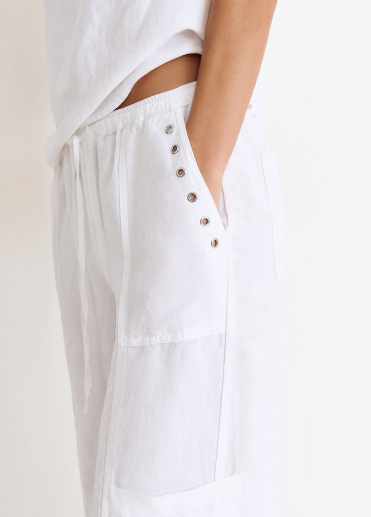 Pantalón bombacho de lino en blanco con detalle de tachas metálicas en el bolsillo lateral