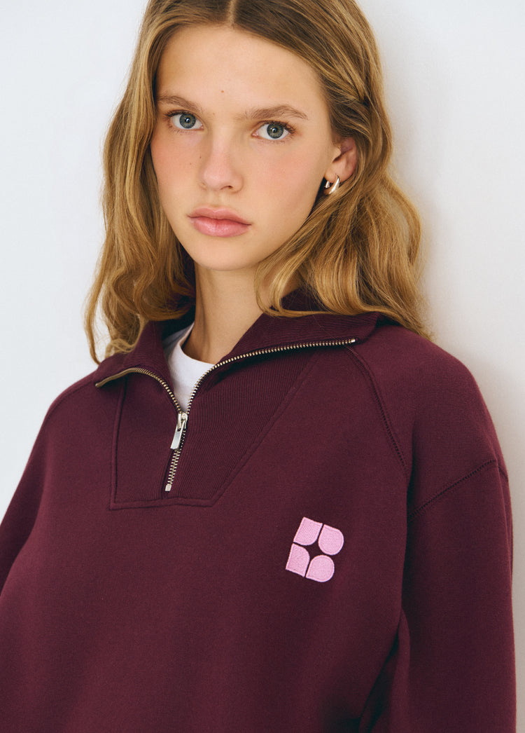 Sudadera de manga larga en tono granate oscuro con cremallera frontal y logo bordado en el pecho