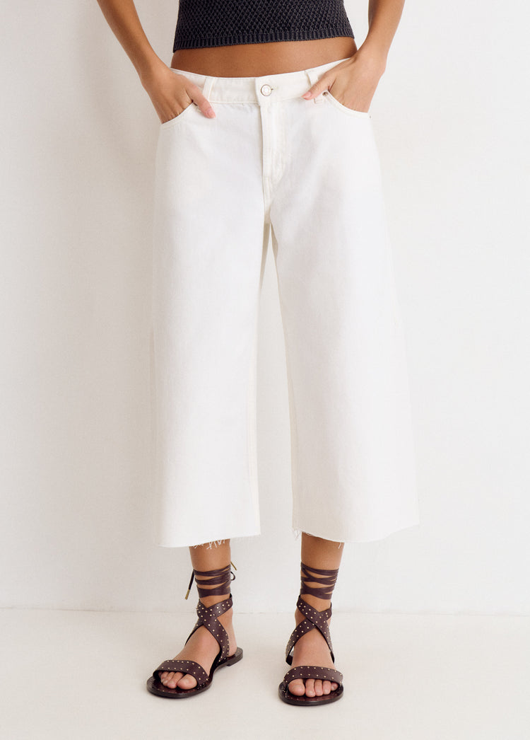 Pantalón culotte blanco de corte amplio y largo por encima del tobillo, con dobladillo deshilachado y bolsillos frontales