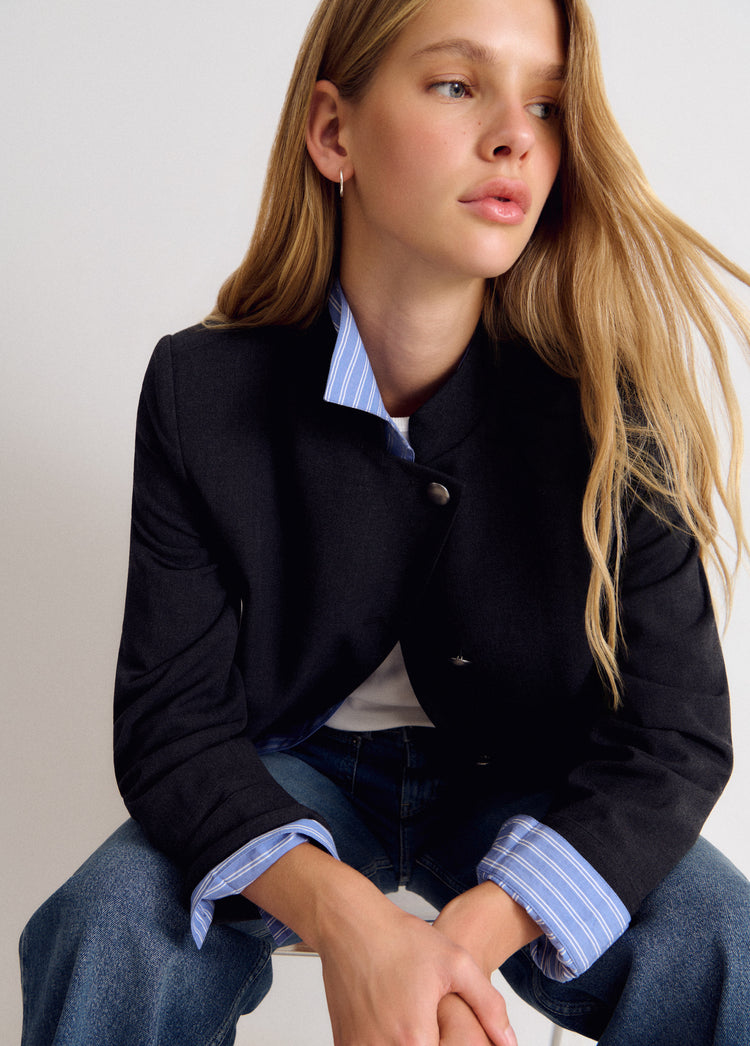 Chaqueta cruzada de color gris medio vista de frente con los puños de rayas azules y blancas asomando