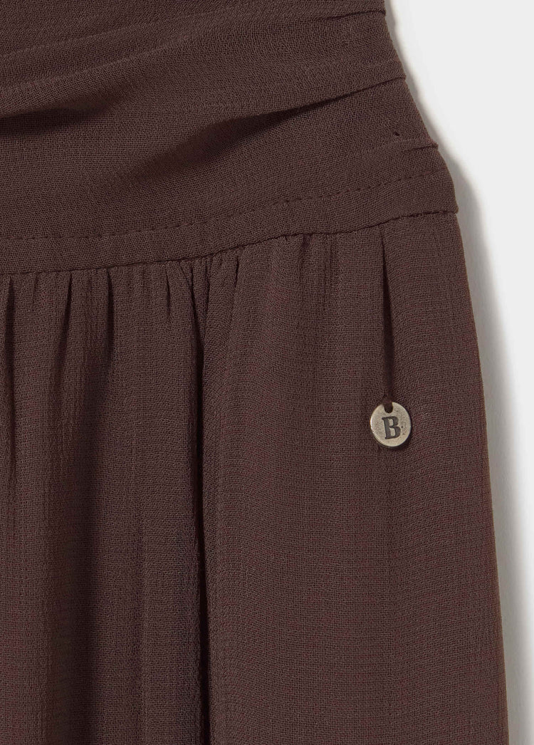 Detalle del vestido frunces largo de color marron con botón decorativo en la parte superior