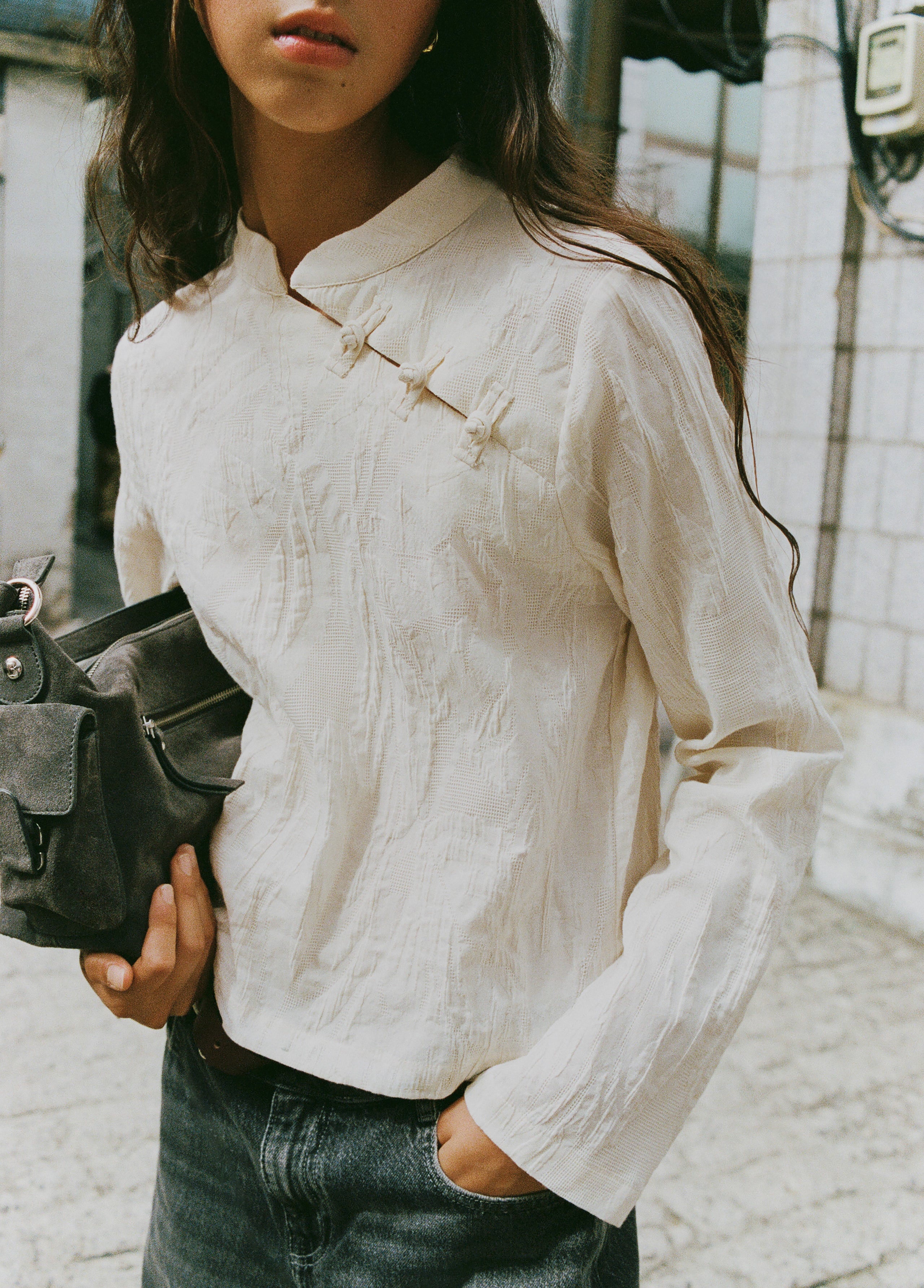 Blusa de manga larga en color crudo con cuello alto y detalle de botones en el pecho