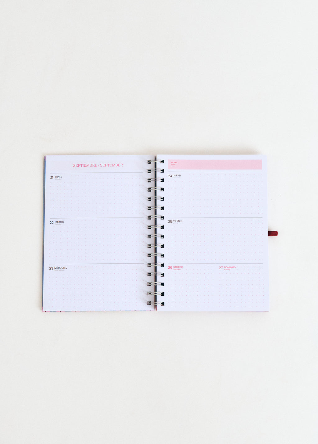 Agenda escolar planner de espiral abierta mostrando las páginas de septiembre en color rosa sobre fondo blanco