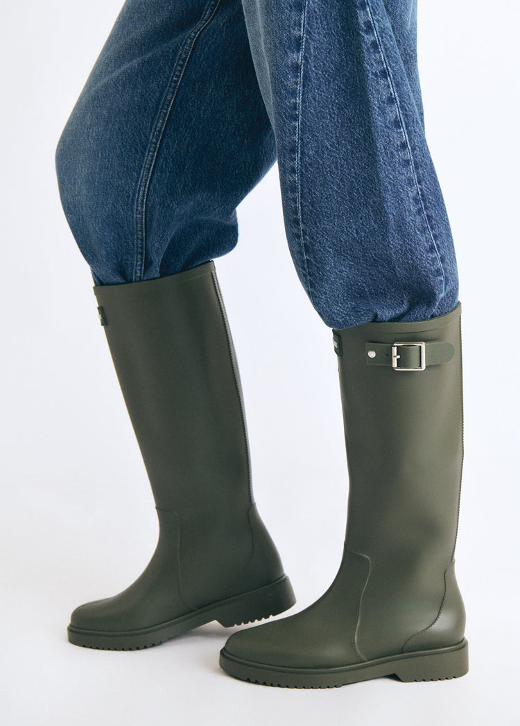 Bota de agua de caña alta en color kaki luciendo su hebilla metálica sobre modelo