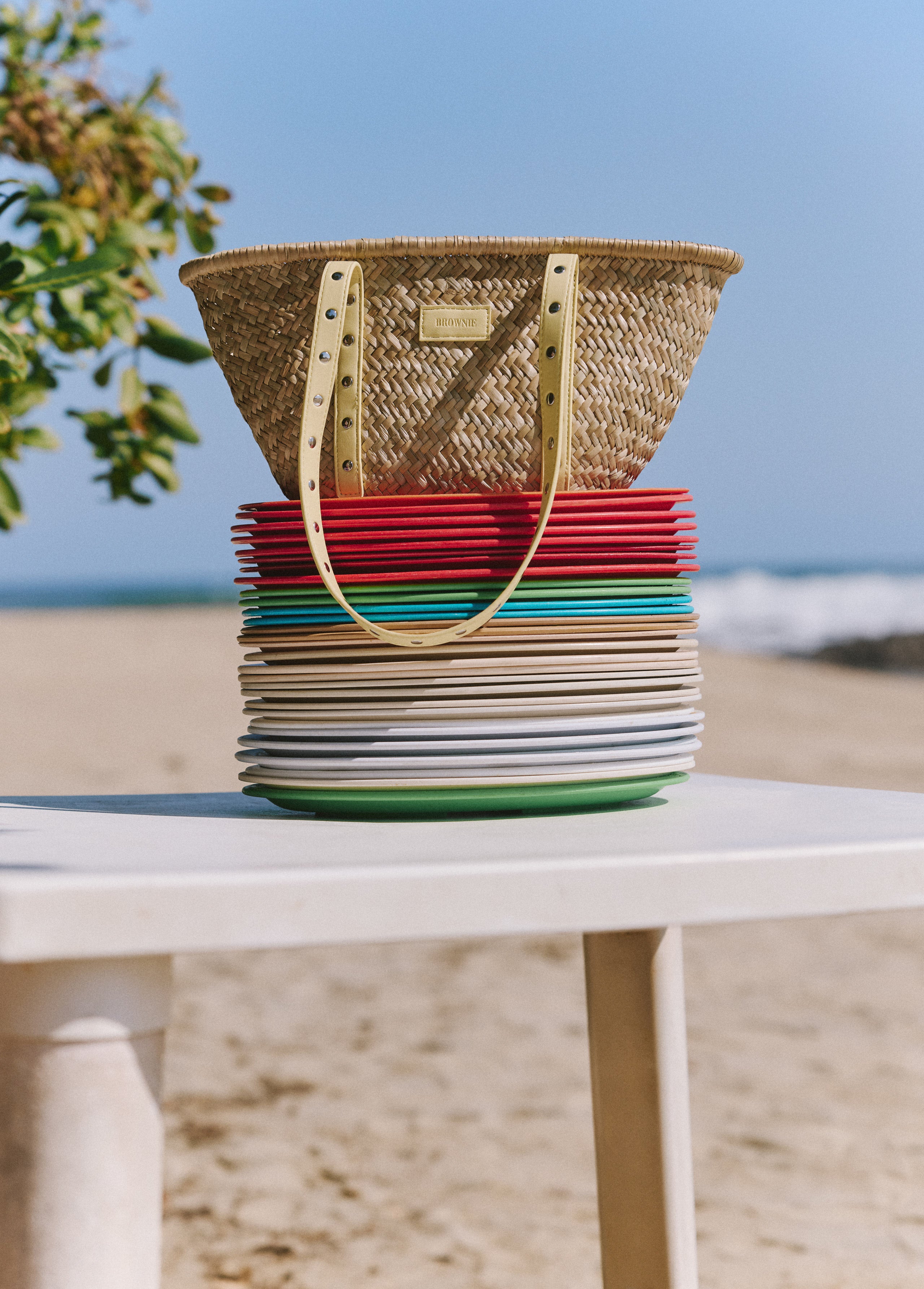Bolso capazo de mimbre en tono natural con tiras de cuero perforado y detalles metálicos