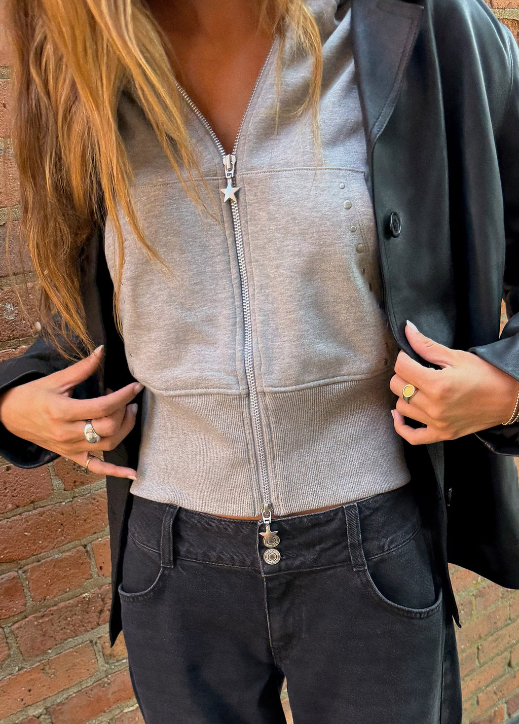 Sudadera gris de cremallera completa con detalle de estrella en el tirante