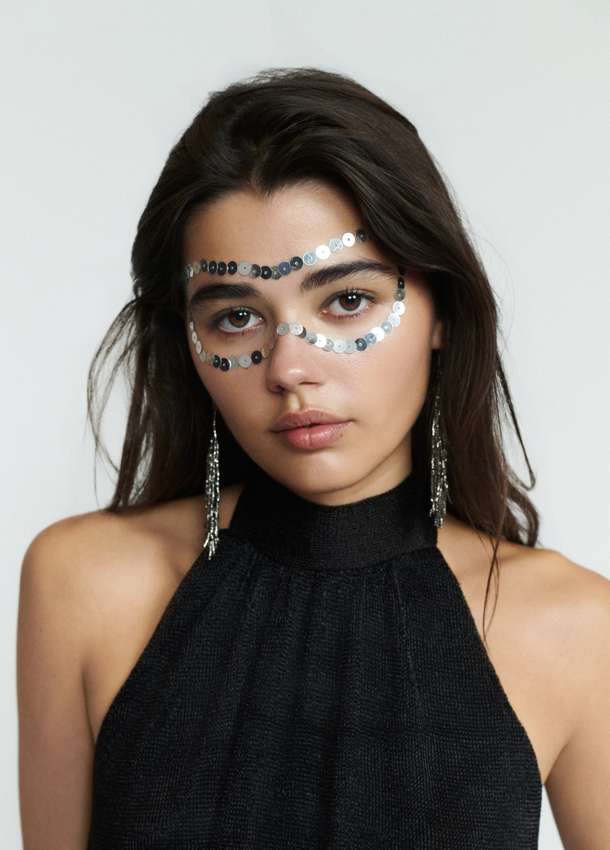 Top halter de brillo en negro sobre modelo con los brazos cruzados