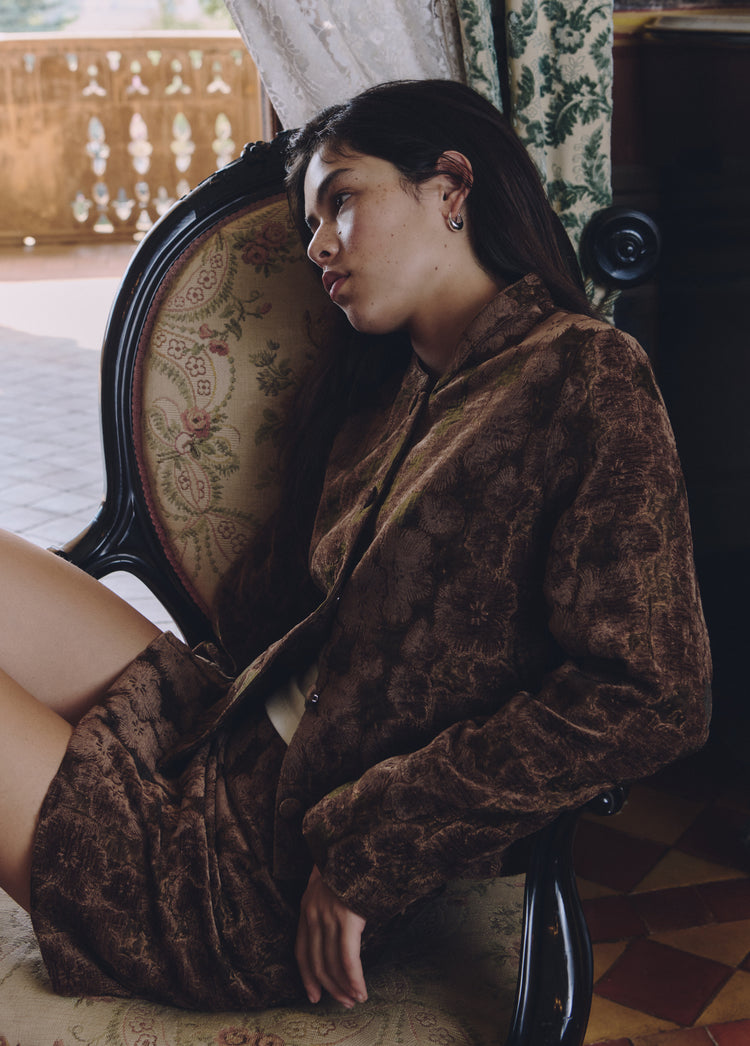 Falda mini de estampado floral en tono terracota vista de perfil sobre una silla tapizada