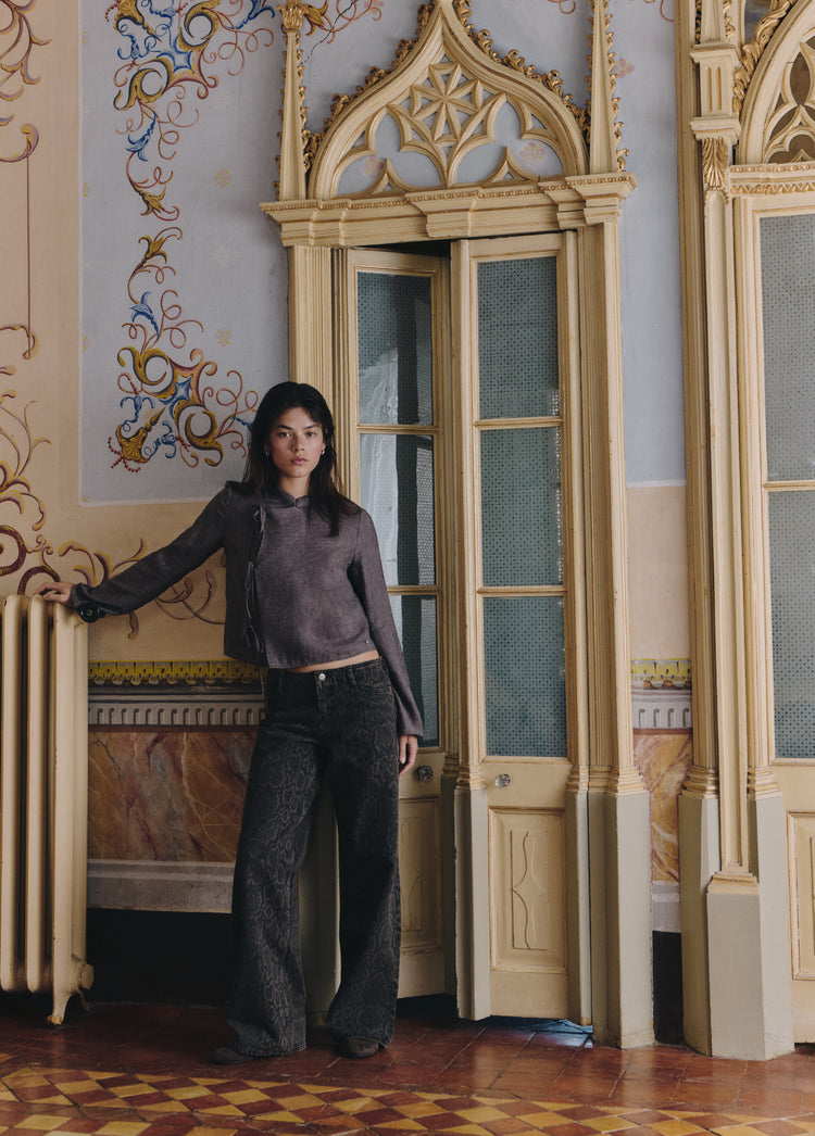 Blusa de punto marrón con detalle de lazos, vista de cuerpo entero en un entorno clásico