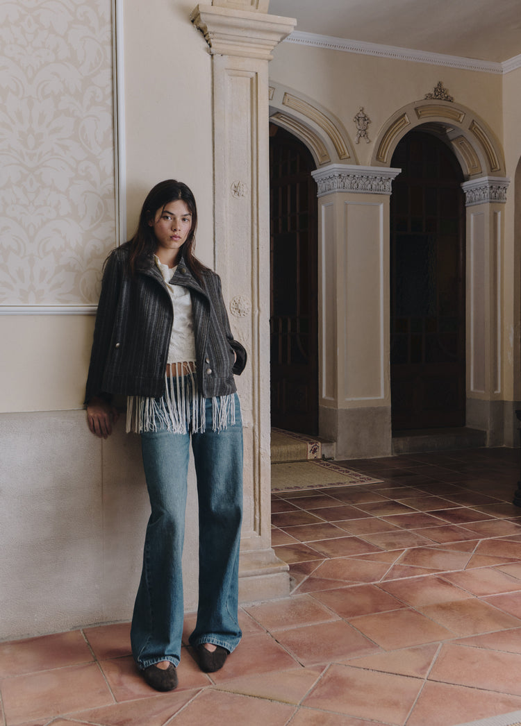Chaqueta de paño abotonada con rayas en gris lucida de cuerpo entero sobre fondo arquitectónico