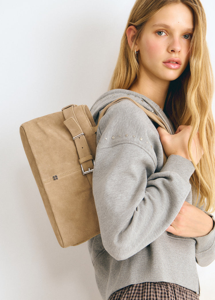 Bolso hombro de color taupe claro con hebilla metálica, visto de perfil sobre el hombro