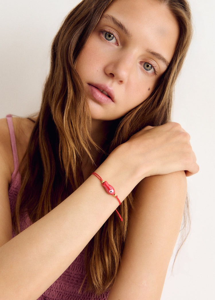 Pulsera de hilo rojo con colgante de pez decorativo lucida sobre la muñeca