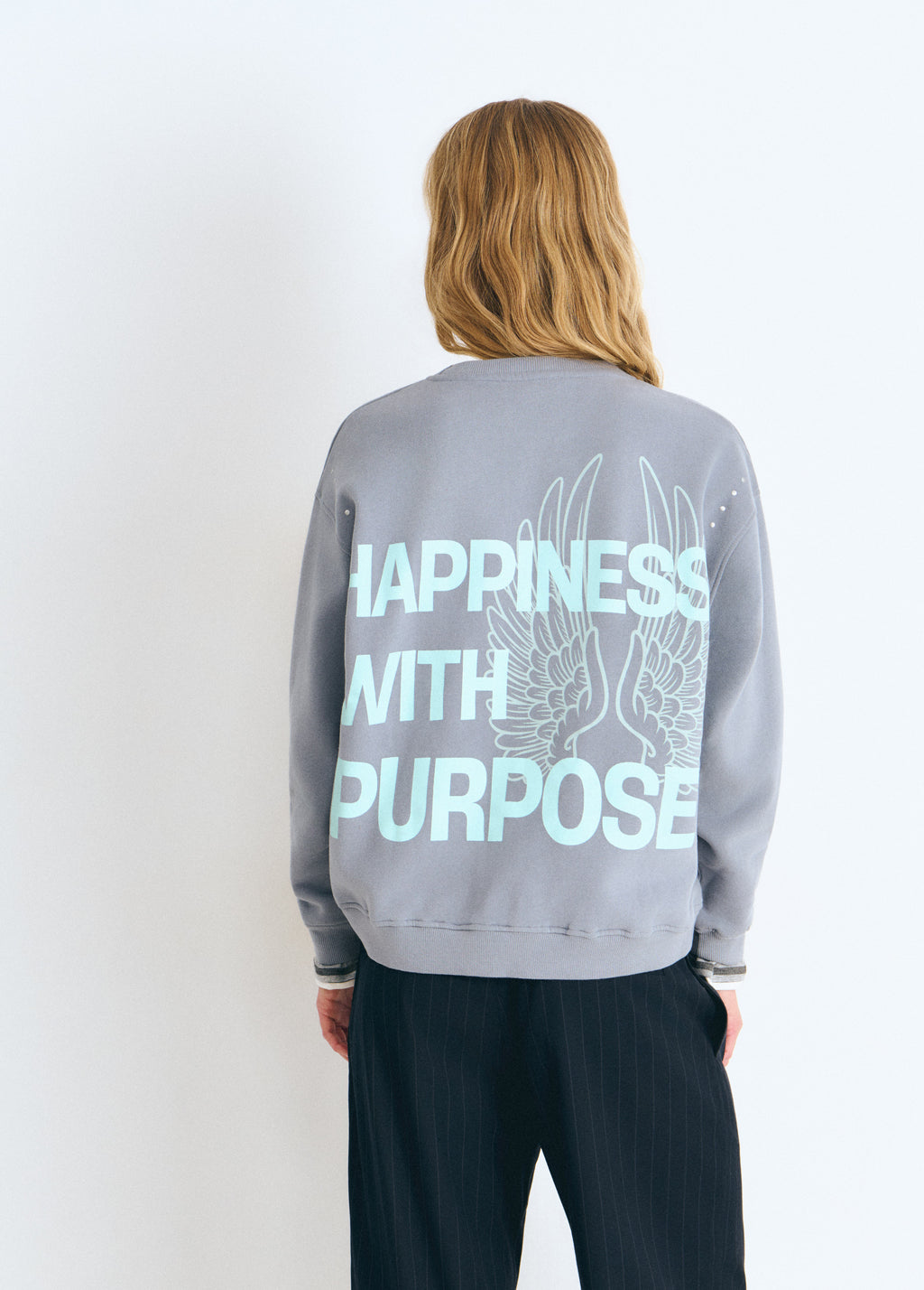 Sudadera gris vista por detrás con estampa de alas glitter y el lema Happiness with Purpose