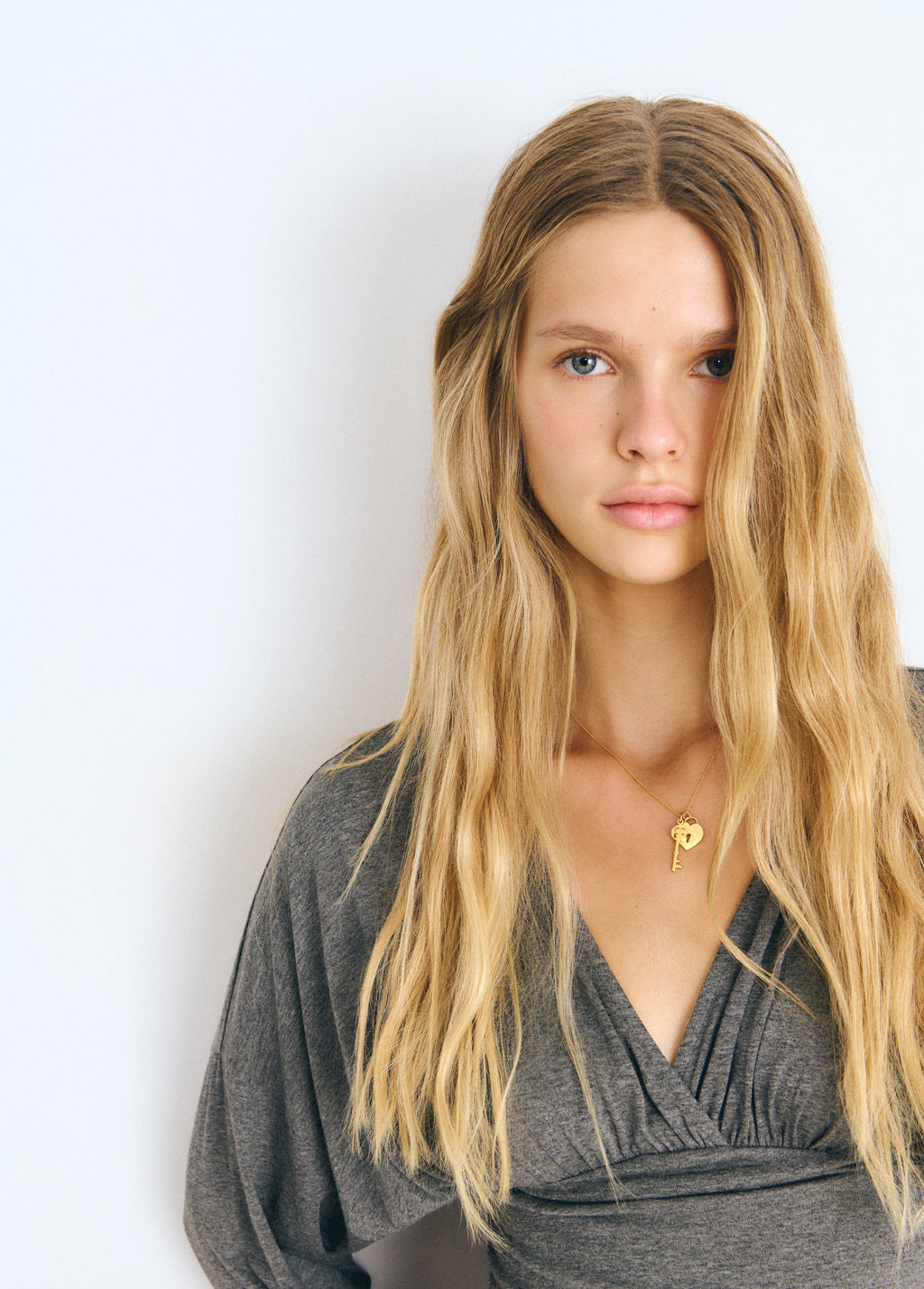 Collar dorado con colgantes de llave y corazón lucido sobre el pecho