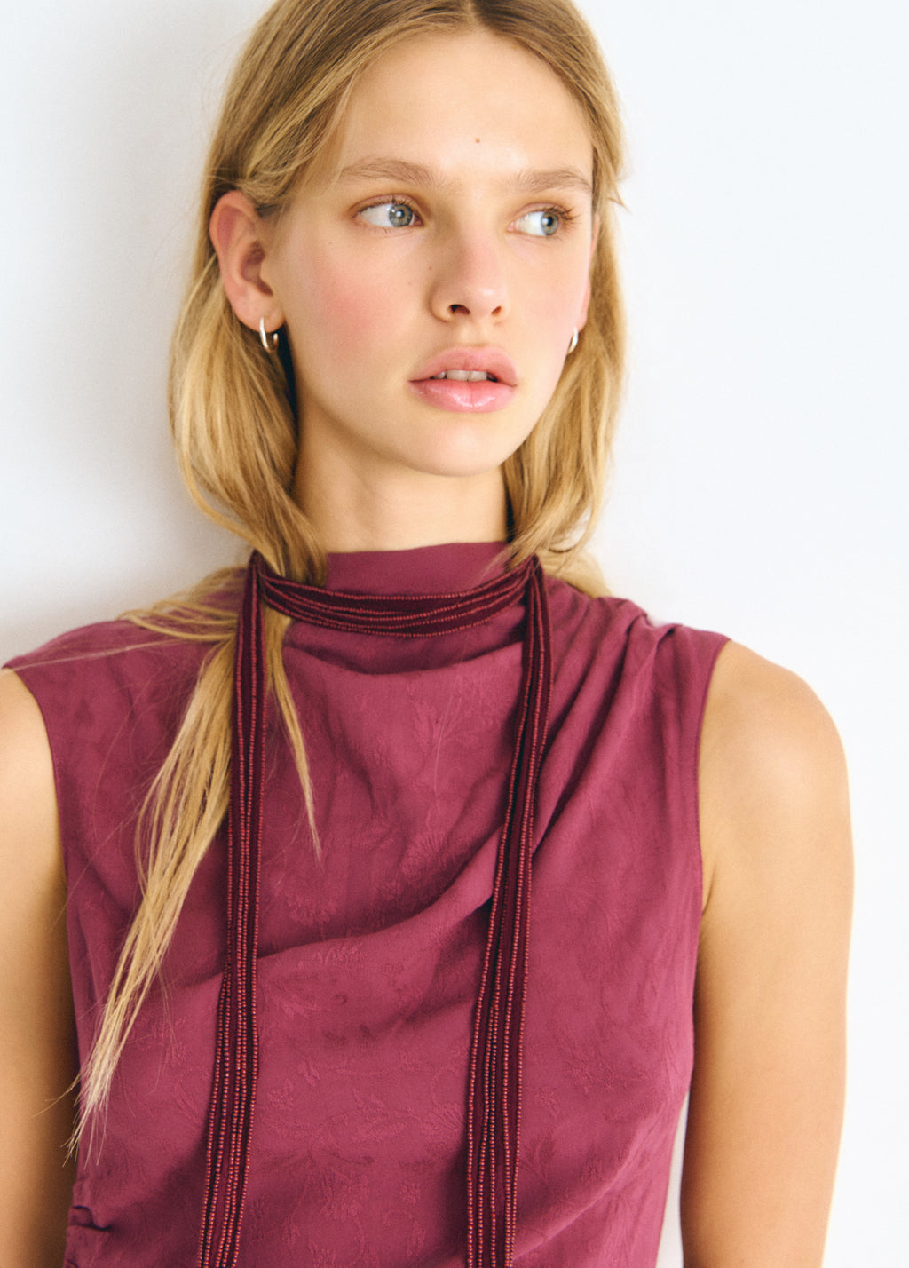 Collar bordado de color granate lucido sobre el cuello de una blusa sin mangas