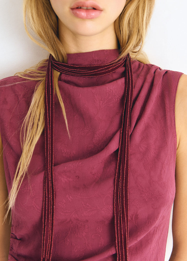 Collar bordado de color granate lucido sobre el cuello de una blusa