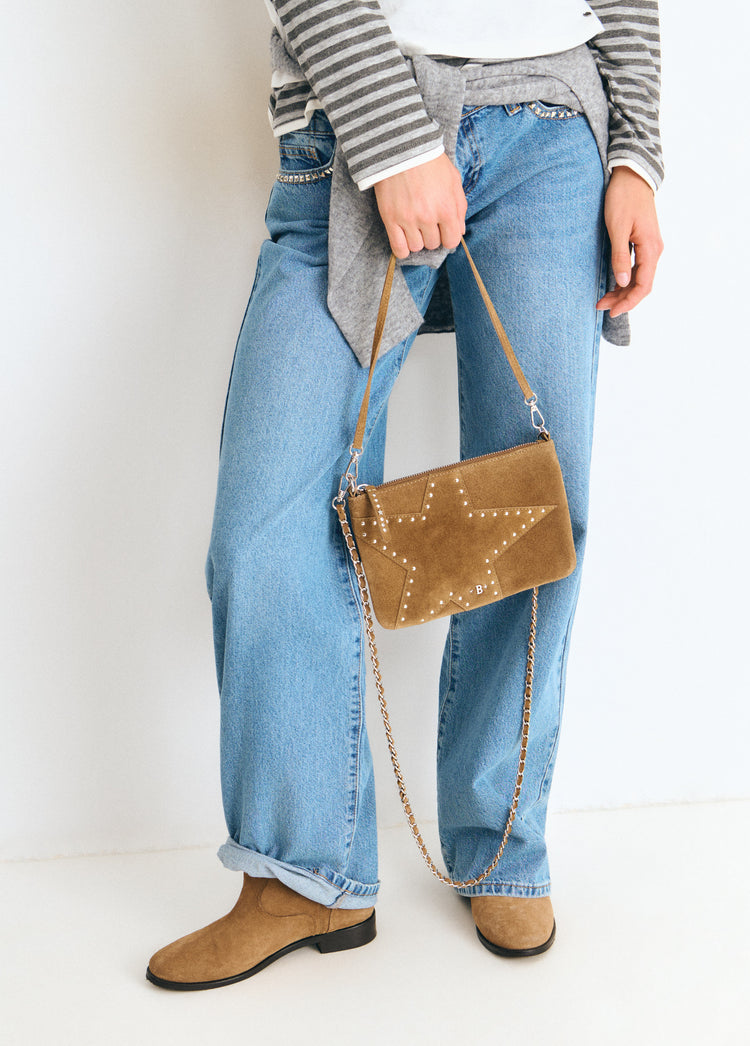 Bolso de forma estrellada en taupe oscuro con tachas y correa metálica colgado del hombro
