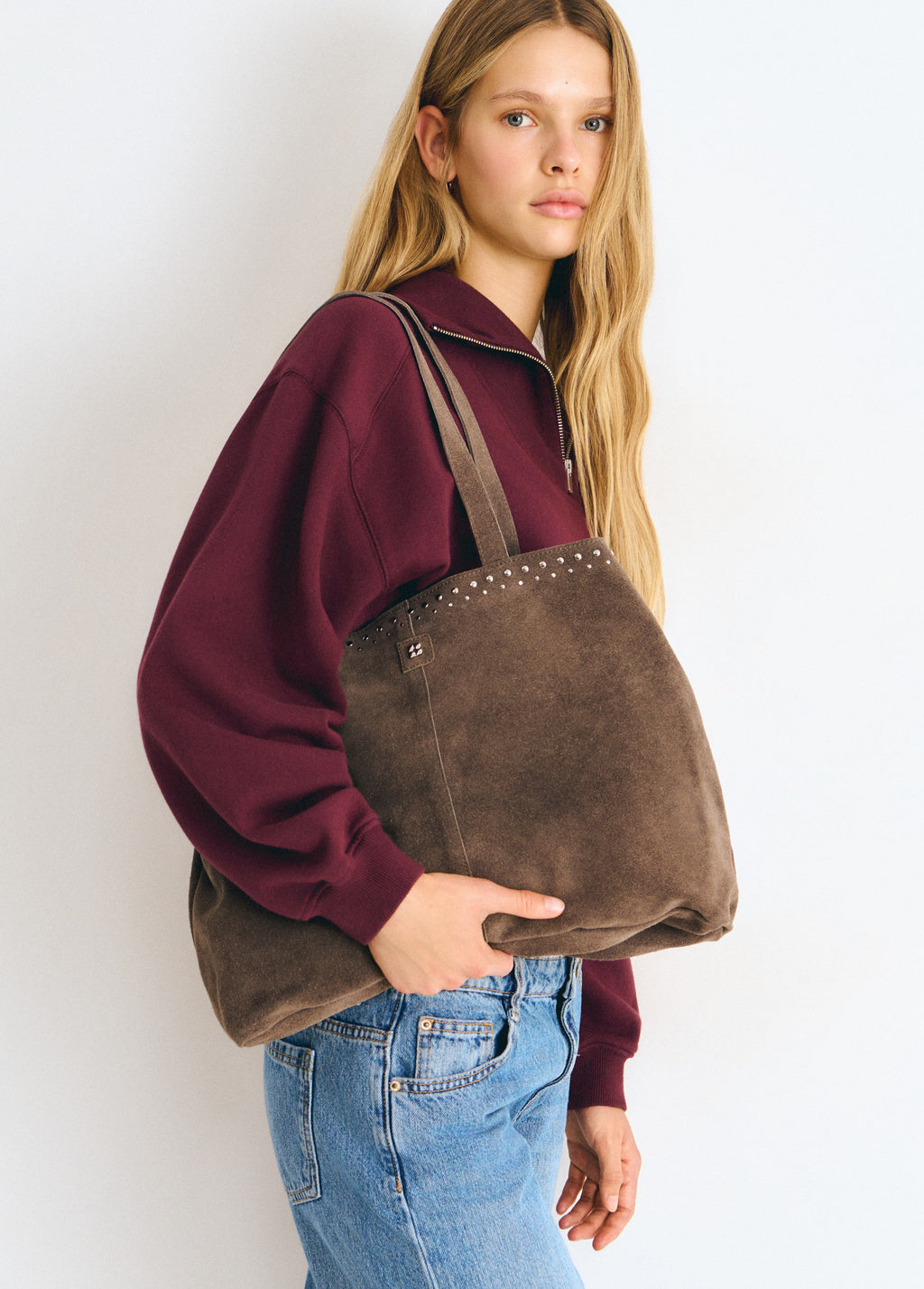 Bolso shopper de color topo con tachas colgado del hombro sobre modelo