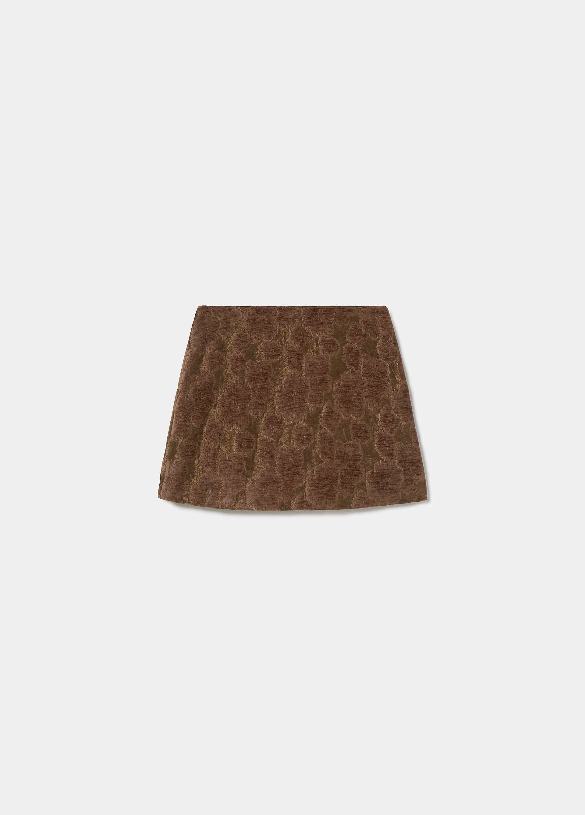 Falda mini de flores en tono terracota vista de perfil sobre una silla de madera