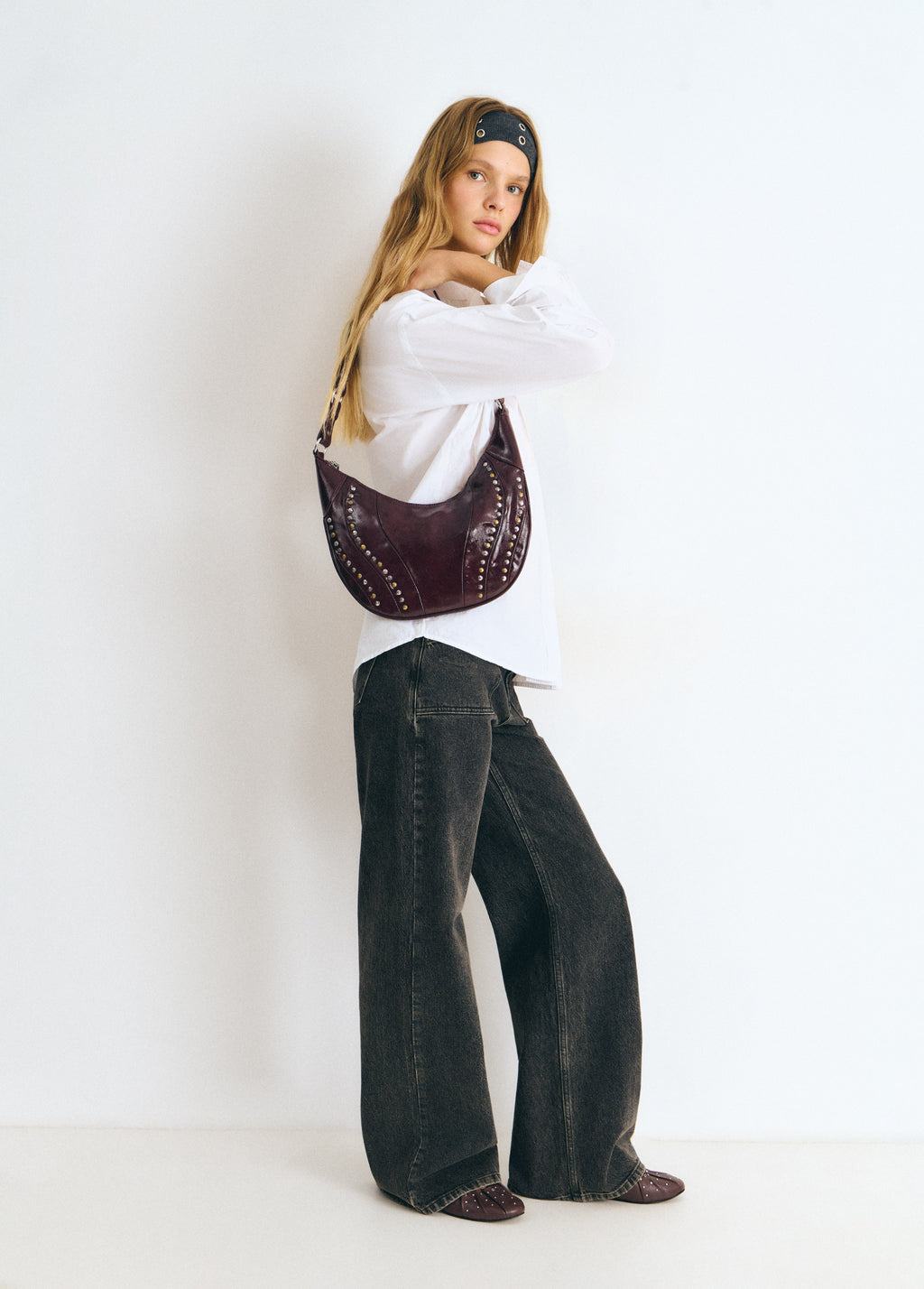 Bolso de hombro en tono granate con remates de tachas lucido en vista lateral