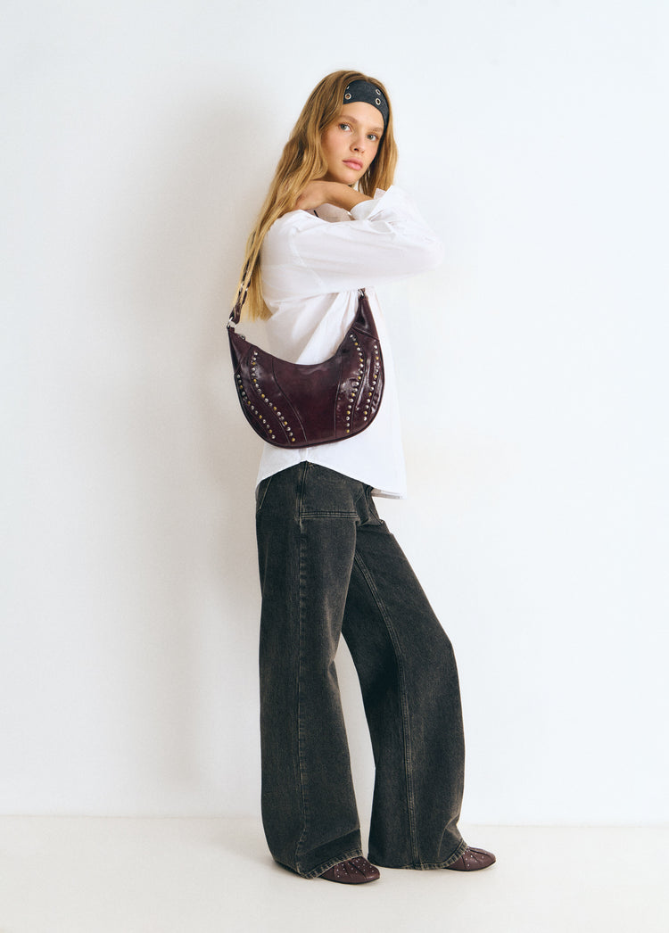 Bolso de hombro en tono granate con remates de tachas lucido en vista lateral