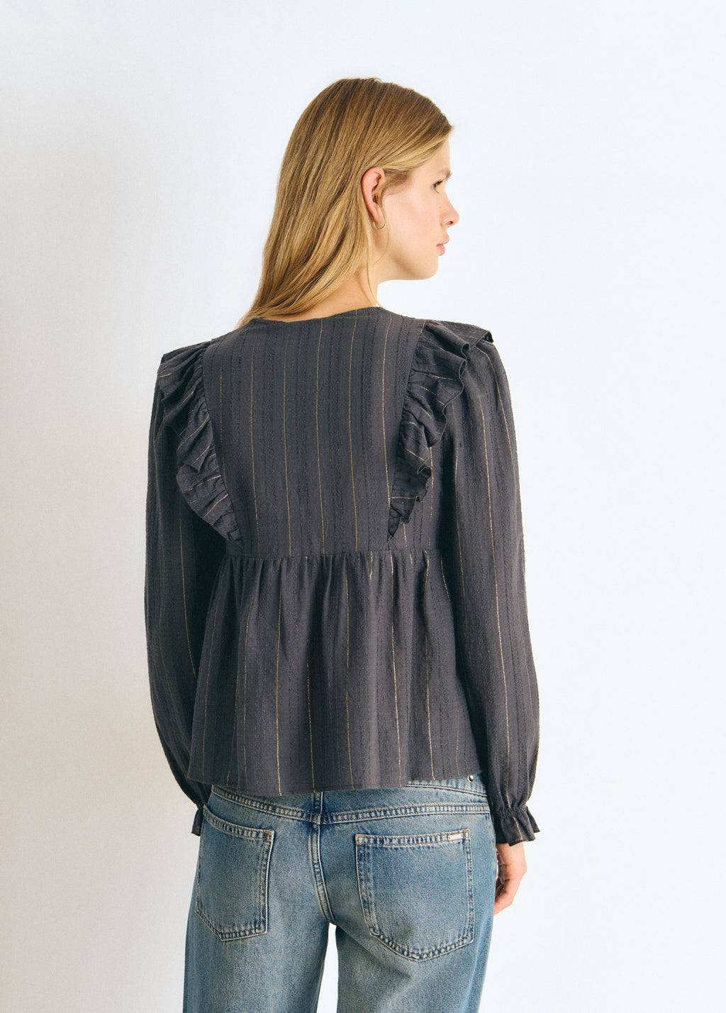 Blusa gris con rayas lurex vista por detrás destacando los volantes en la espalda