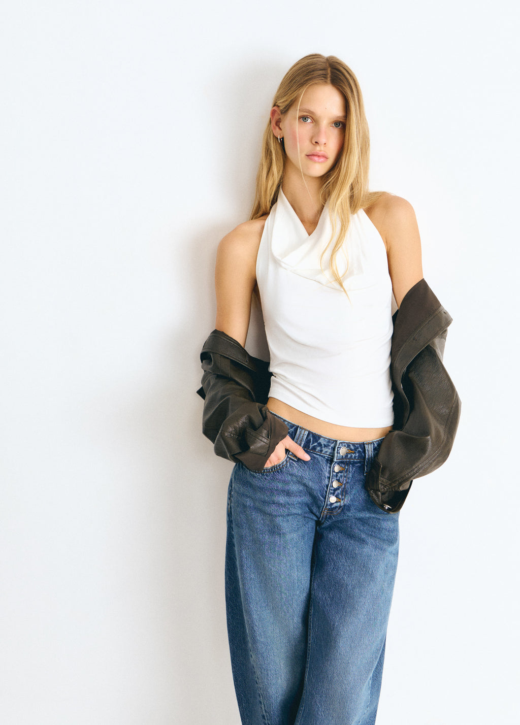 Top blanco de cuello halter con caída en el escote, luciendo su diseño ajustado y moderno