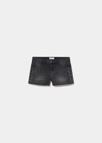 Short negro de vaqueros con tachas en los laterales visto de frente