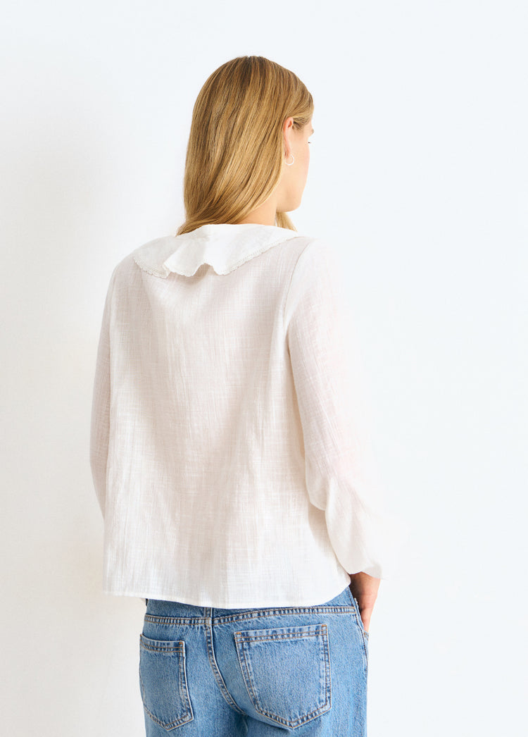 Blusa blanca de manga larga vista por la espalda con cuello volante