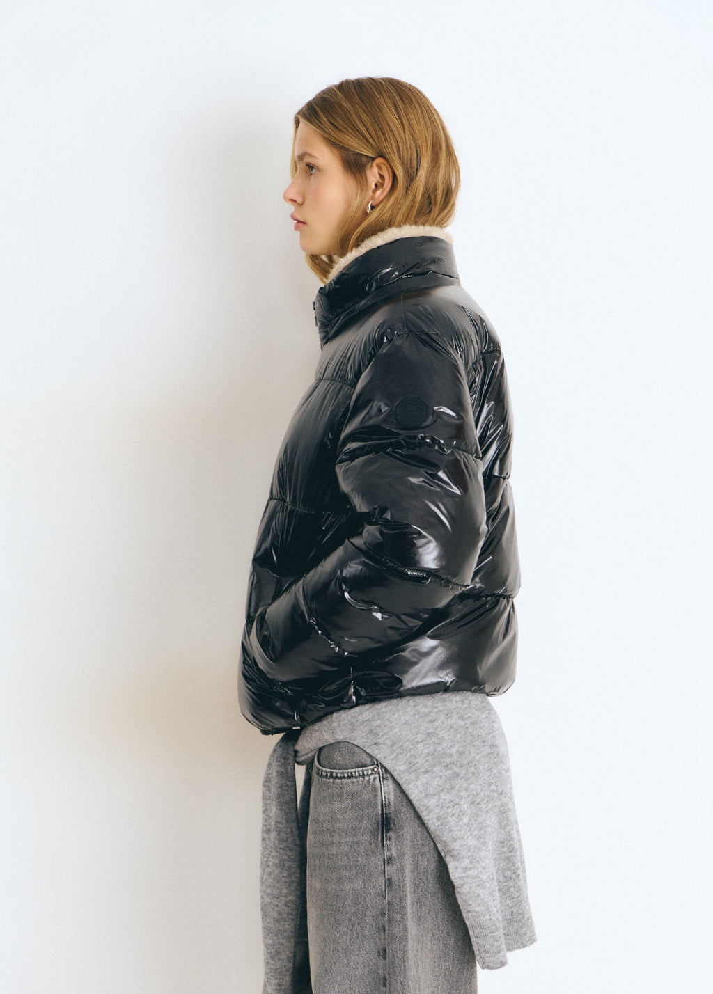 Chaqueta acolchada de vinilo negro vista de perfil con cuello alto y forro interior visible