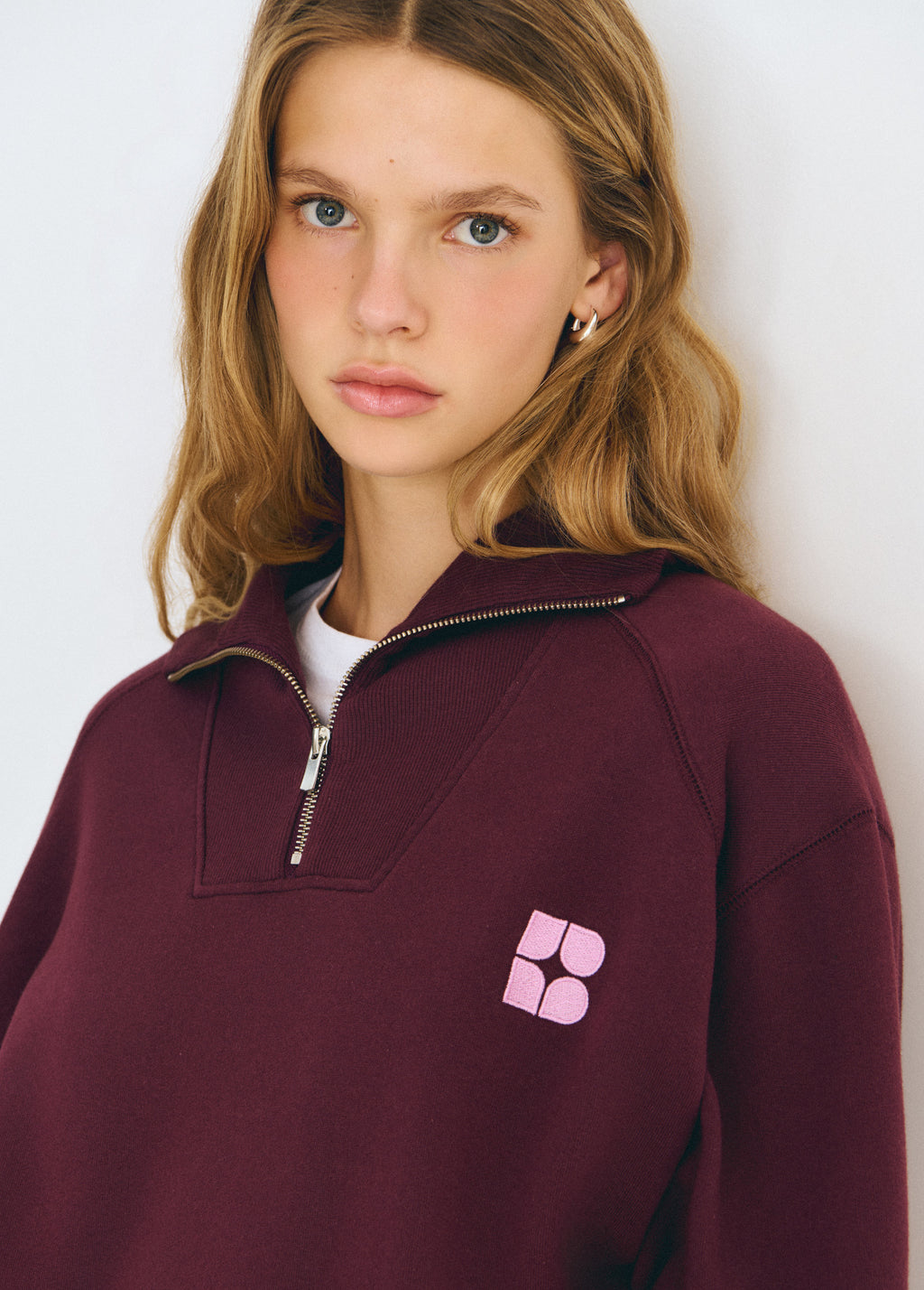 Sudadera de manga larga en tono granate oscuro con cremallera frontal y logo bordado en el pecho