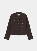 Chaqueta marrón de doble botonadura metálica vista frontal con los puños en los bolsillos