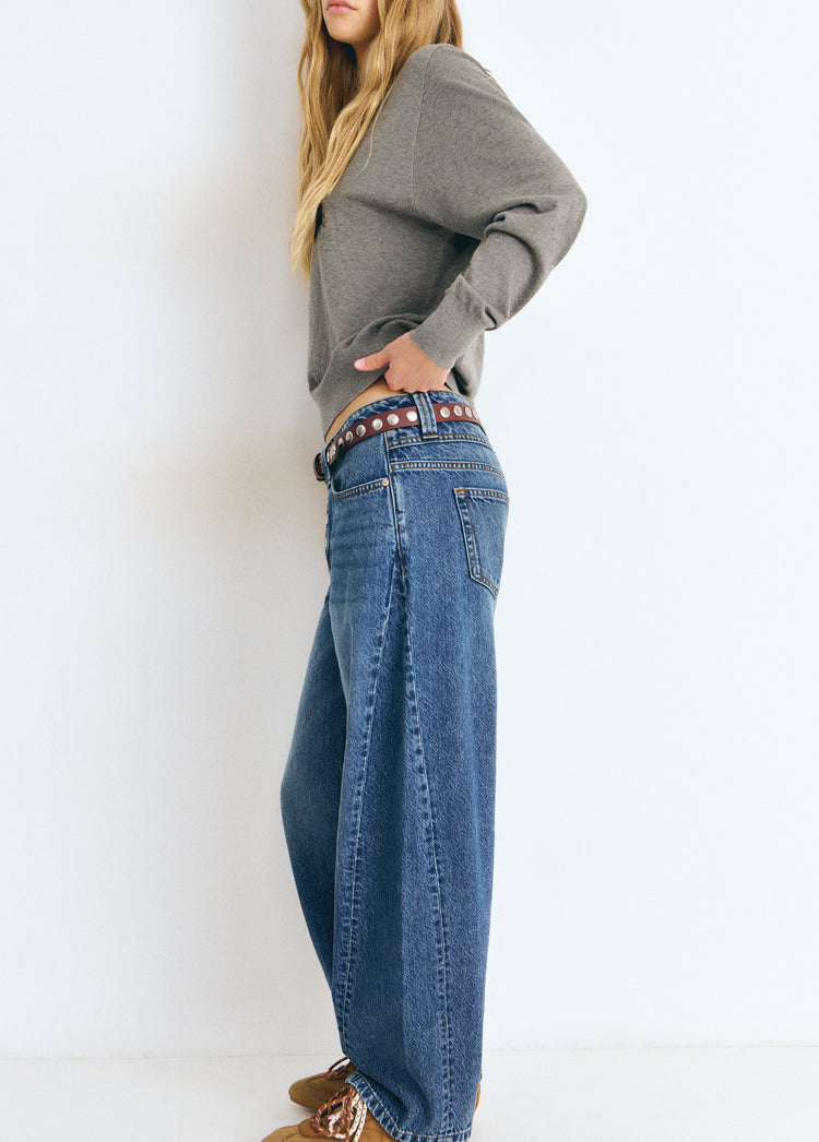 Pantalón vaquero barrel de azul medio visto de perfil con cinturón de tachuelas