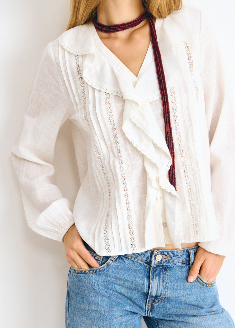Blusa blanca de manga larga con volantes y bordados en el frente