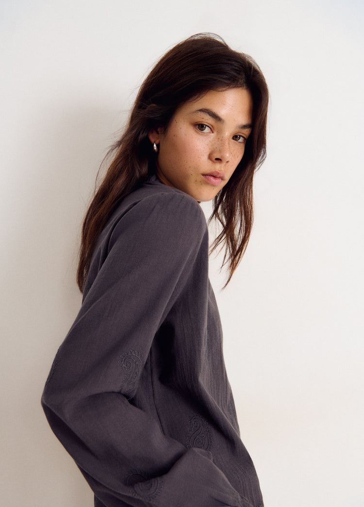 Blusa de manga larga en gris con bordado sutil en la parte inferior