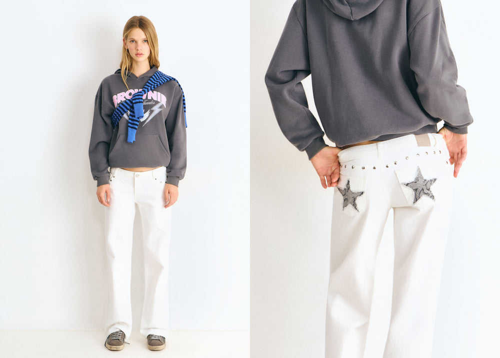 Pantalón blanco de tiro bajo con estrellas glitter y tachas luciendo su caída recta en vista frontal