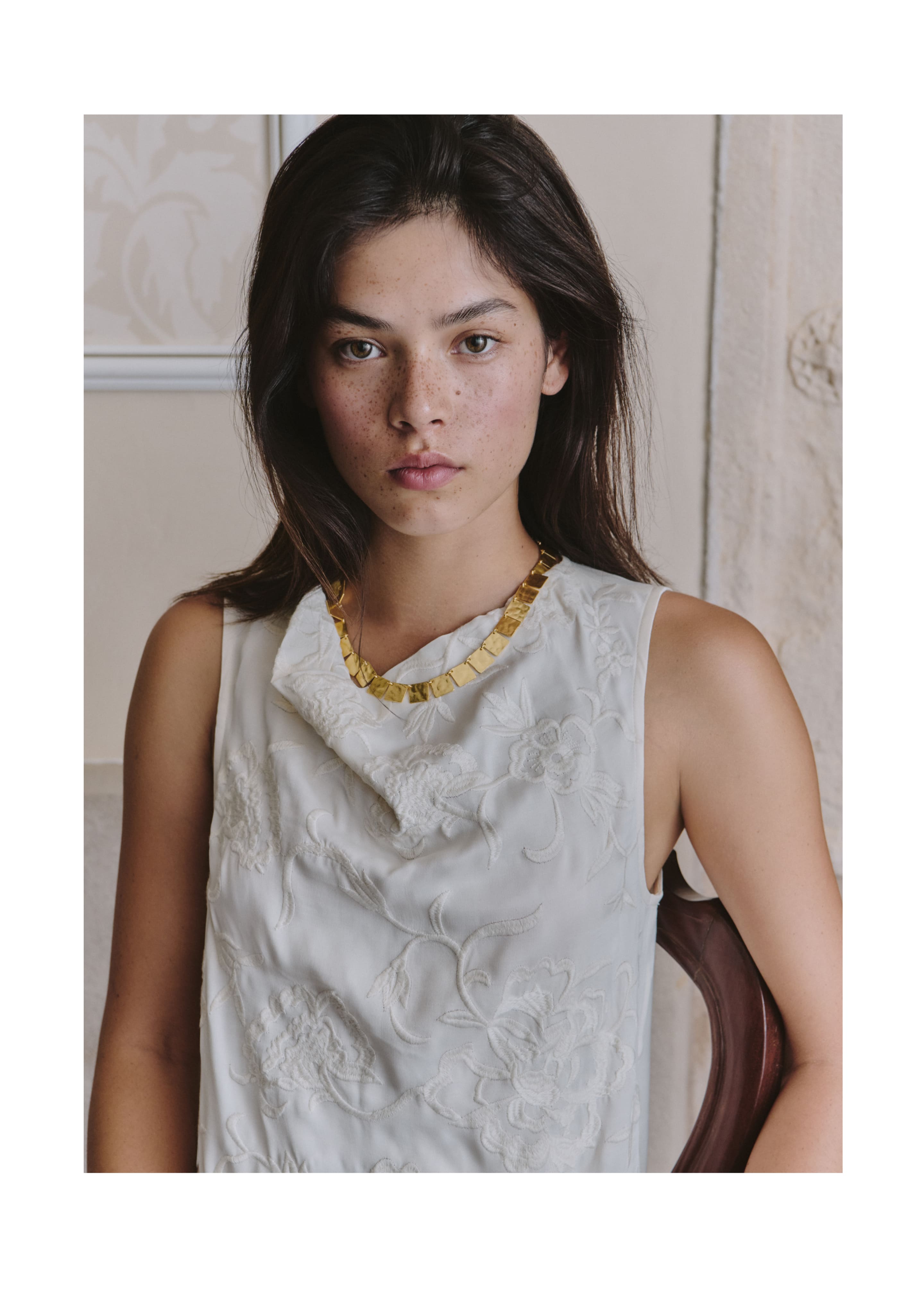 Collar dorado de eslabones cuadrados lucido sobre un top blanco de encaje floral